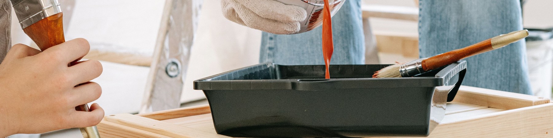 Pouring paint into a tray, brushes and a stepladder nearby