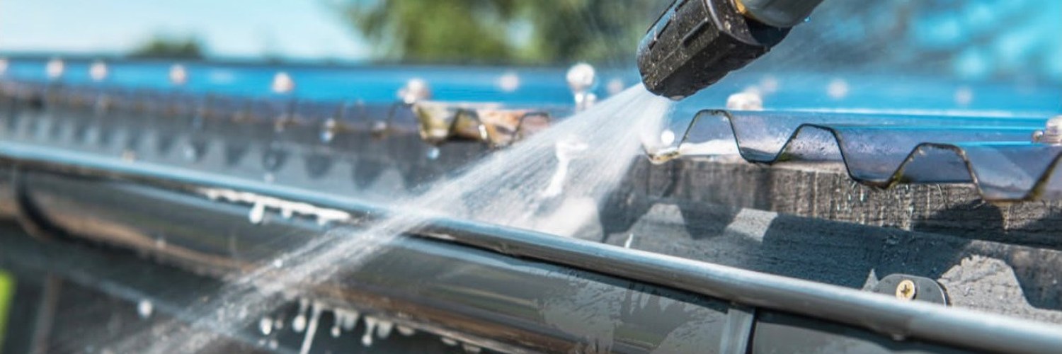 Gutter being cleared and flushed with a pressure washer